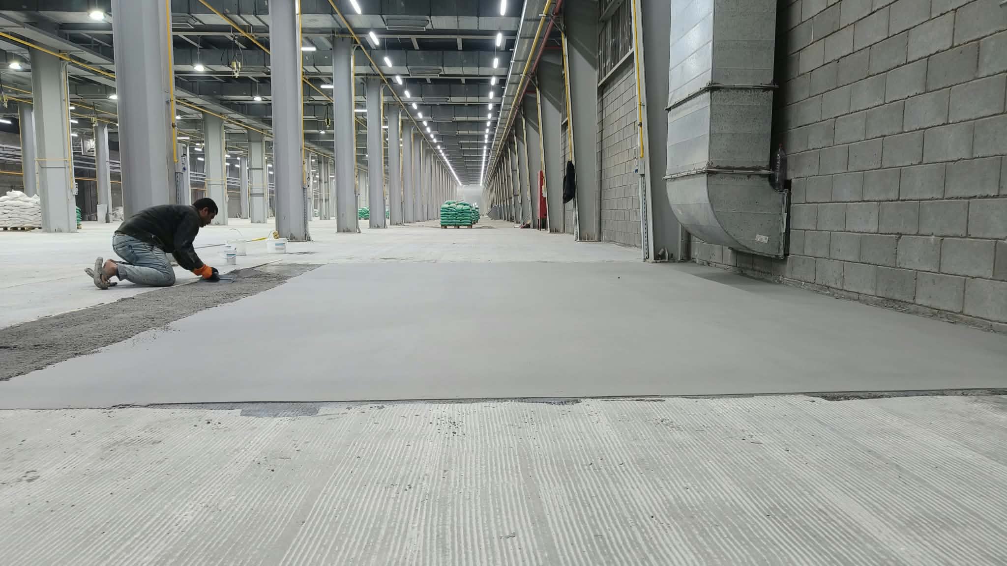 Worker screeding a large warehouse floor ahead of epoxy application
