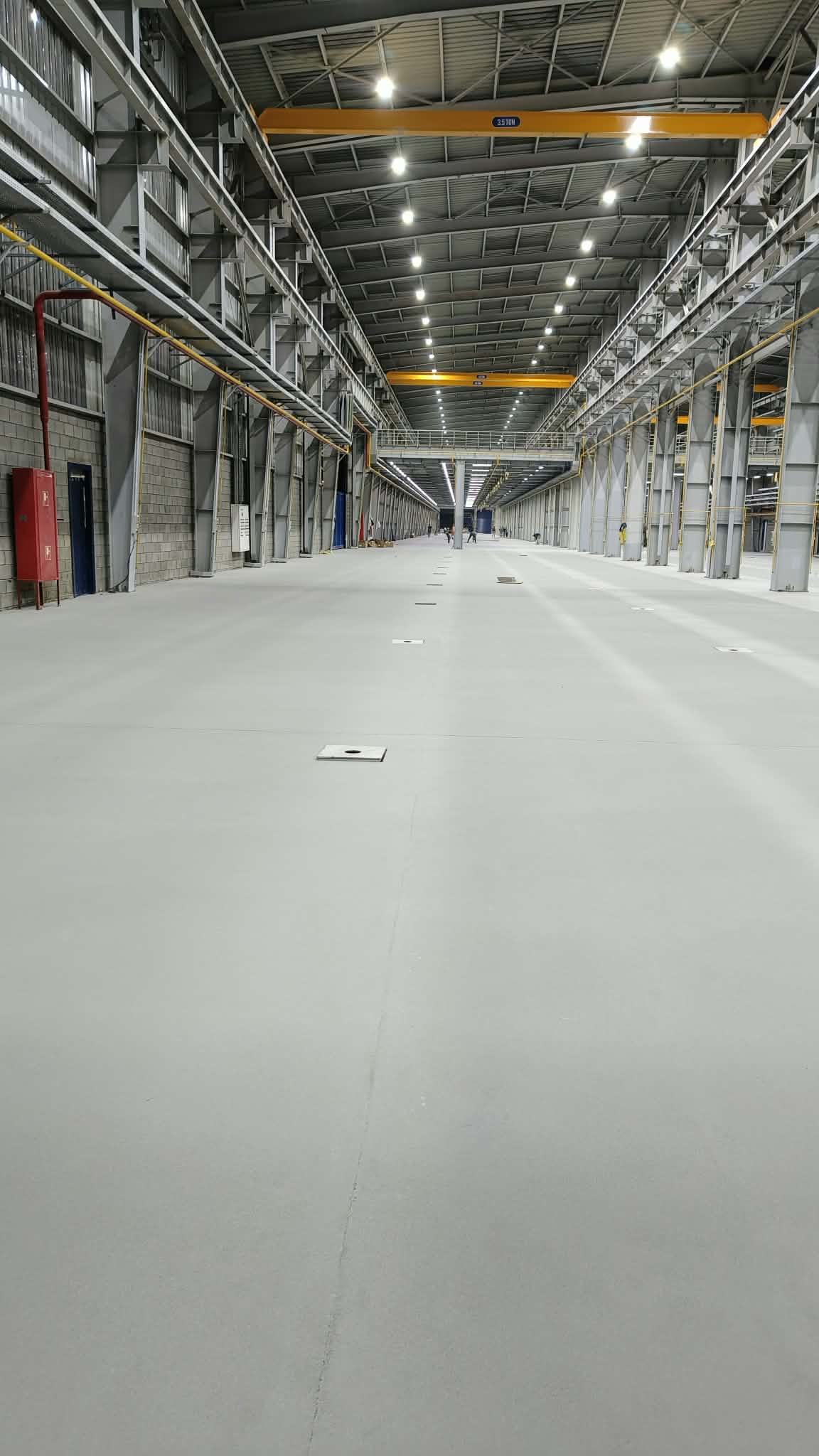 Long factory aisle with finished epoxy flooring and overhead crane rails