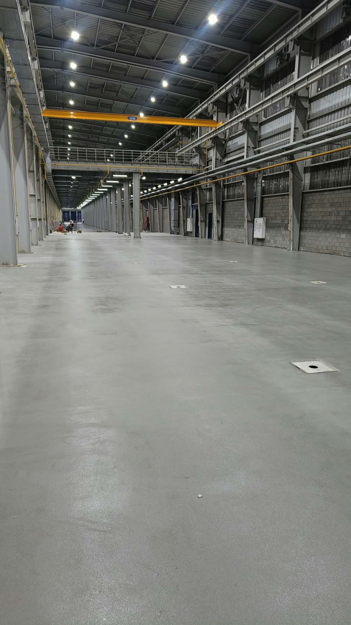 Wide factory aisle with finished epoxy flooring, view toward mezzanine