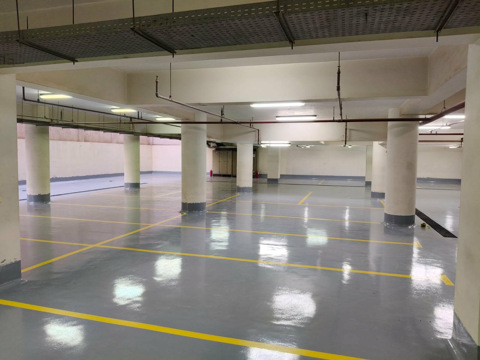 Glossy grey epoxy floor in a parking garage with yellow bay markings
