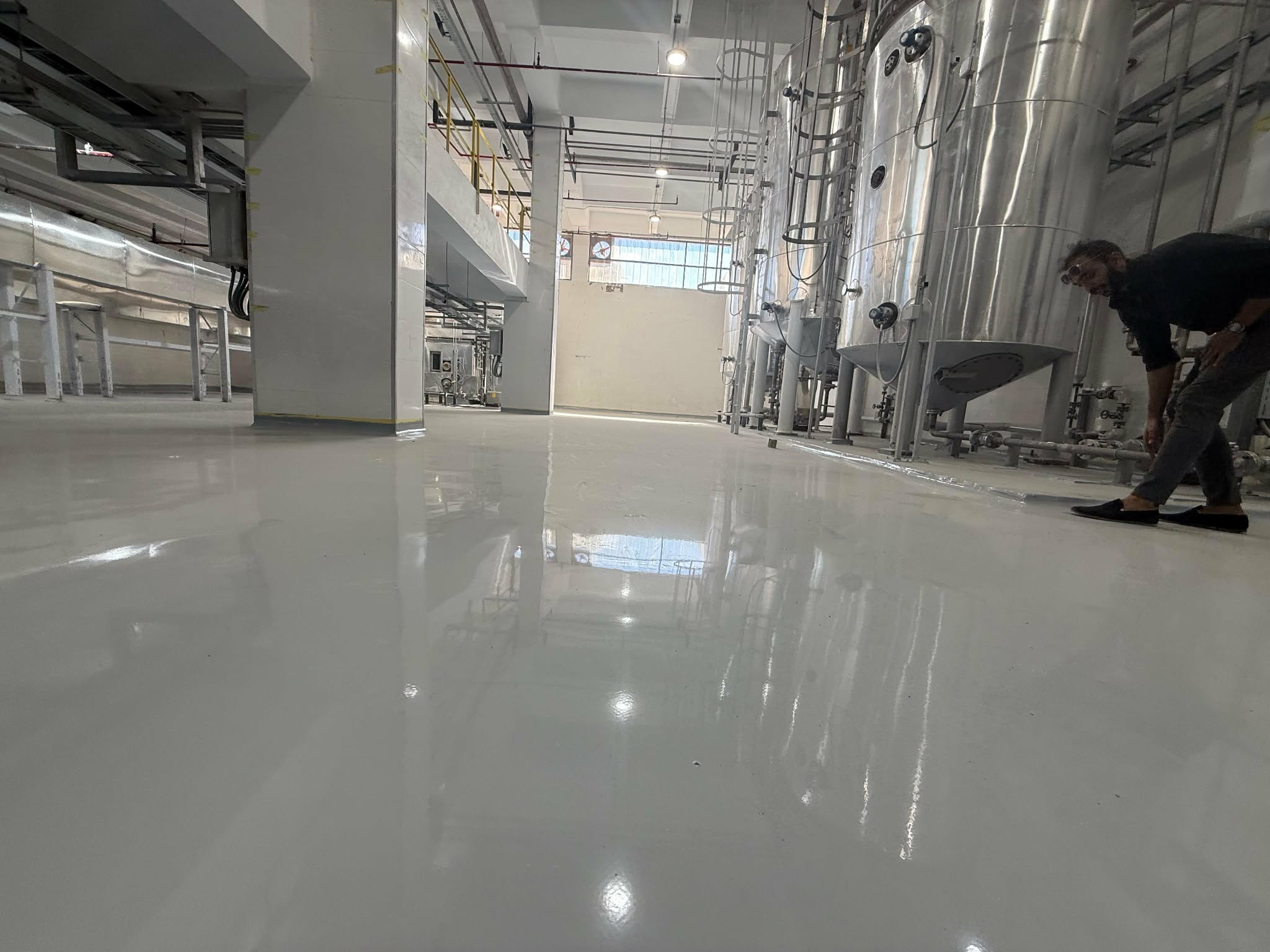 Glossy epoxy floor in a processing plant with stainless steel tanks